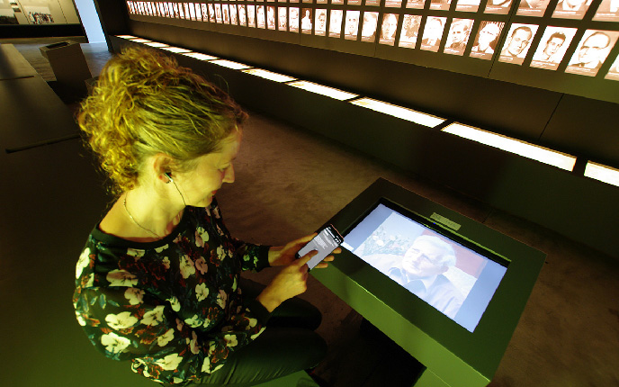 Besucherin bedient eine digitale Medienstation mit dem Smartphone